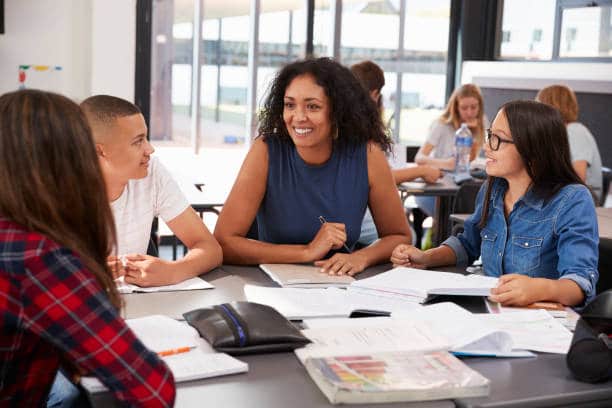 A teacher teaching and helping students in small group 